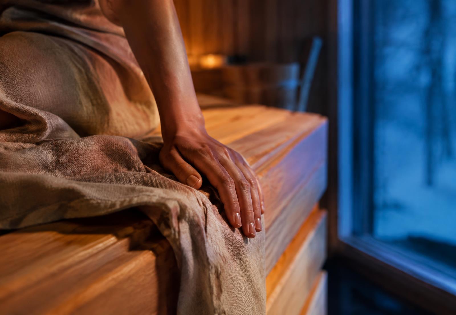 Hand resting on a warm sauna bench beside a cool window